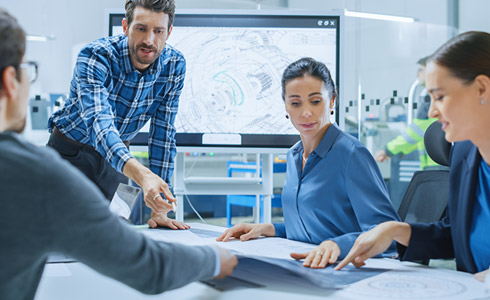 Team in technischer Besprechung mit Konstruktionsunterlagen – Symbolbild für erfolgreiche PLM-Projekte und partnerschaftliche Zusammenarbeit mit ECS.